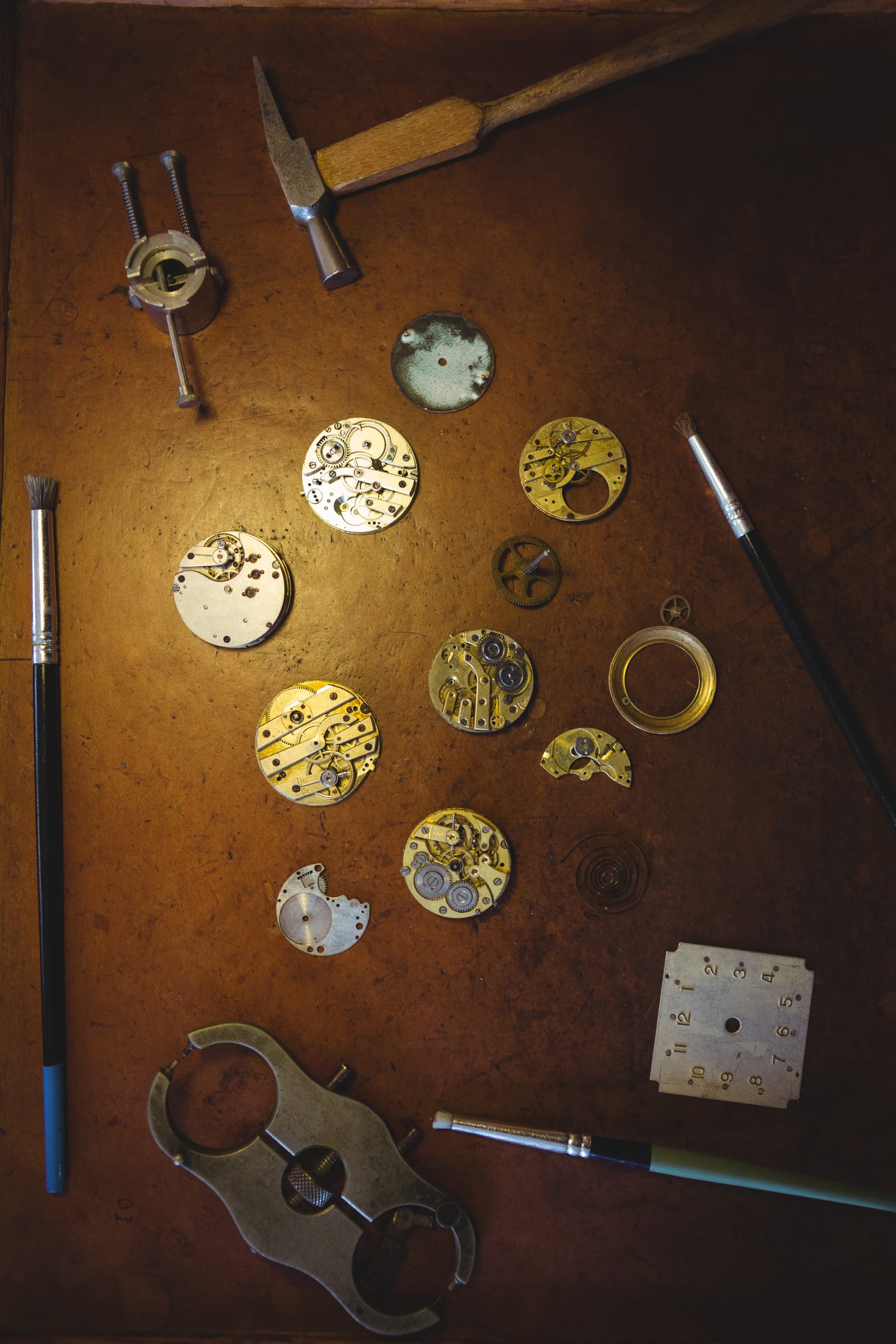 Strumenti di misurazione allineati su un banco grigio con un orologio in lavorazione